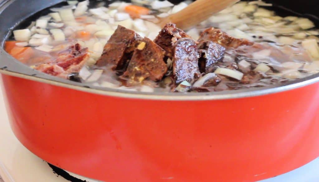 bacon bones in soup pot with diced onions and water